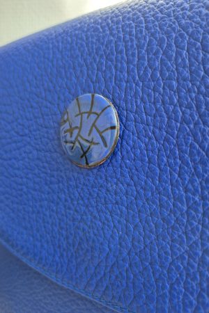 Close-up of the limited-edition sgraffito enamel button on the Cobalta Sigillum leather saddle bag