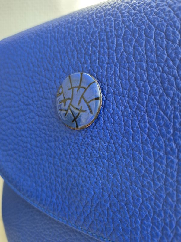 Close-up of the limited-edition sgraffito enamel button on the Cobalta Sigillum leather saddle bag