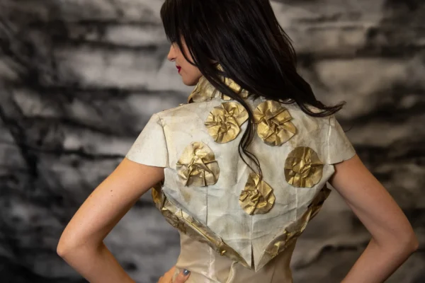 Model wearing Canvas Bolero, crafted from oil-painted fabric using the crumpled sewing application technique. Back view.