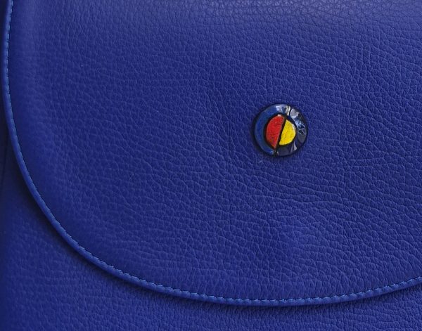 Close-up of the limited-edition sgraffito enamel button on the Azura Enigma leather saddle bag