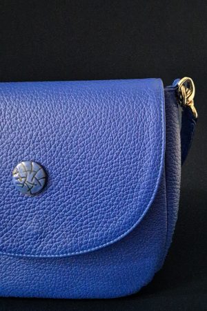 Close-up of the limited-edition sgraffito enamel button on the Cobalta Sigillum leather saddle bag