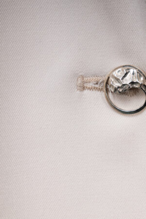 lose-up of the soft ecru fabric and the single Yin-Yang silver button detail on the Argentum Signatum suit jacket.