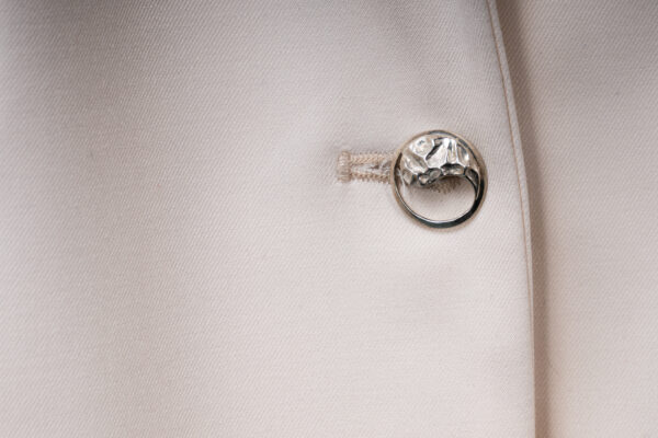 lose-up of the soft ecru fabric and the single Yin-Yang silver button detail on the Argentum Signatum suit jacket.