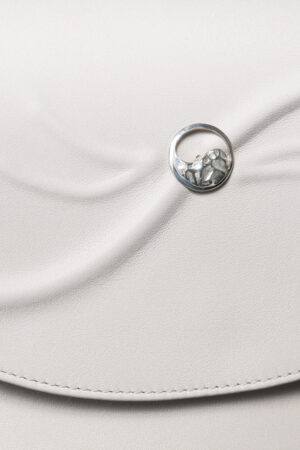 Close-up of the 925 sterling silver Yin-Yang button on the beige leather Serenitas bag.