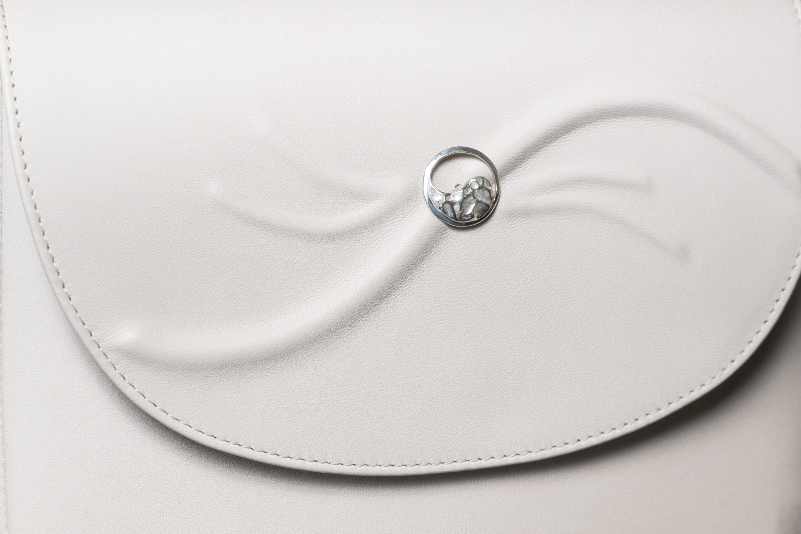Close-up of the 925 sterling silver Yin-Yang button on the beige leather Serenitas bag.