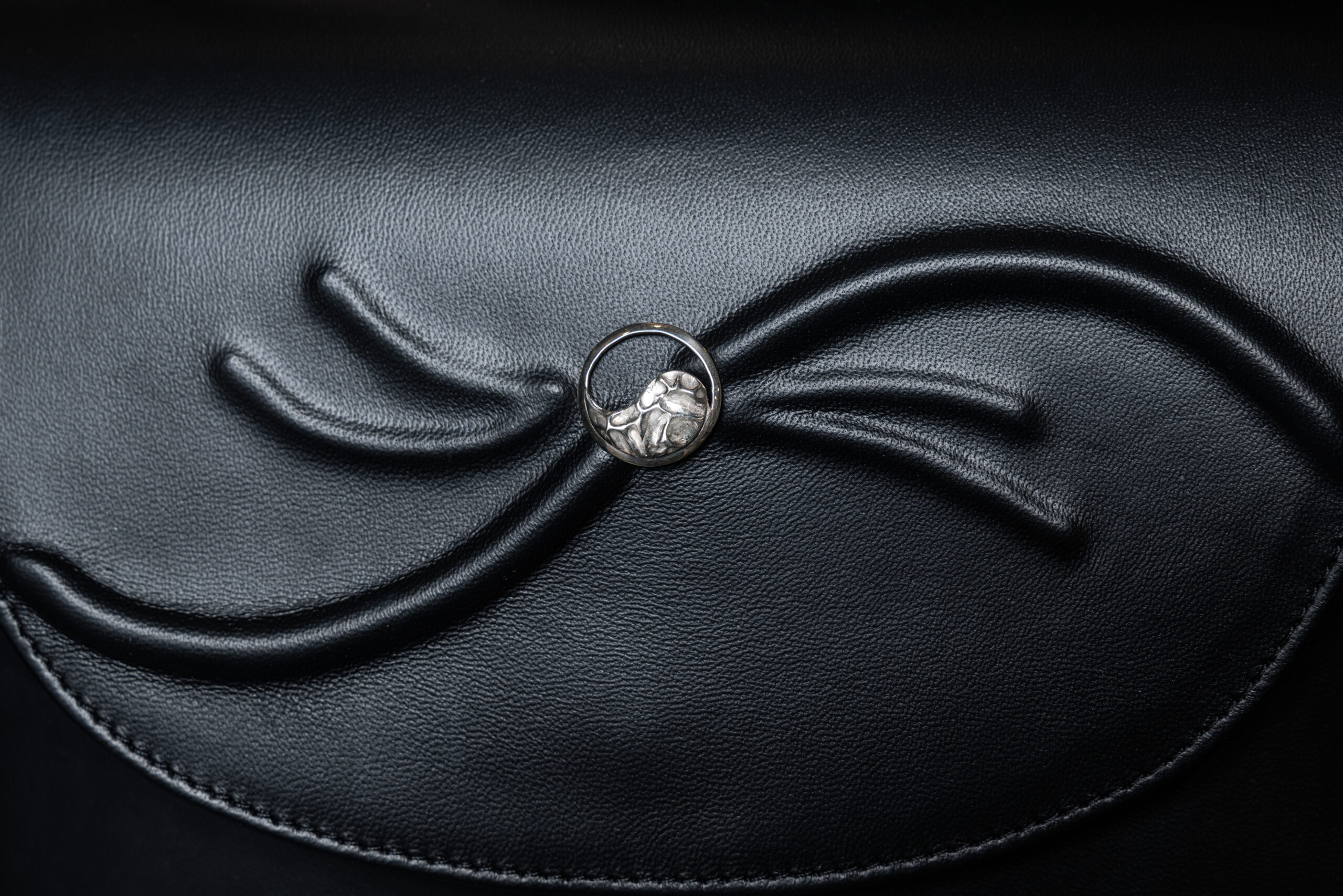 Close-up of the sterling silver Yin-Yang button on the black leather Luminis bag.