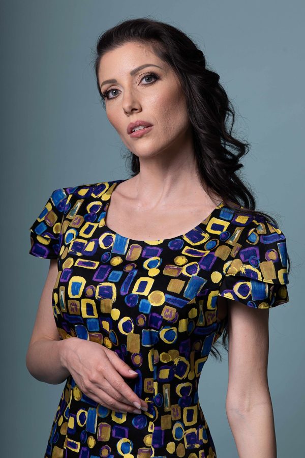 Product picture: Model wearing the Flos Umbrae dress, full-length shot, capturing the dramatic sleeves.