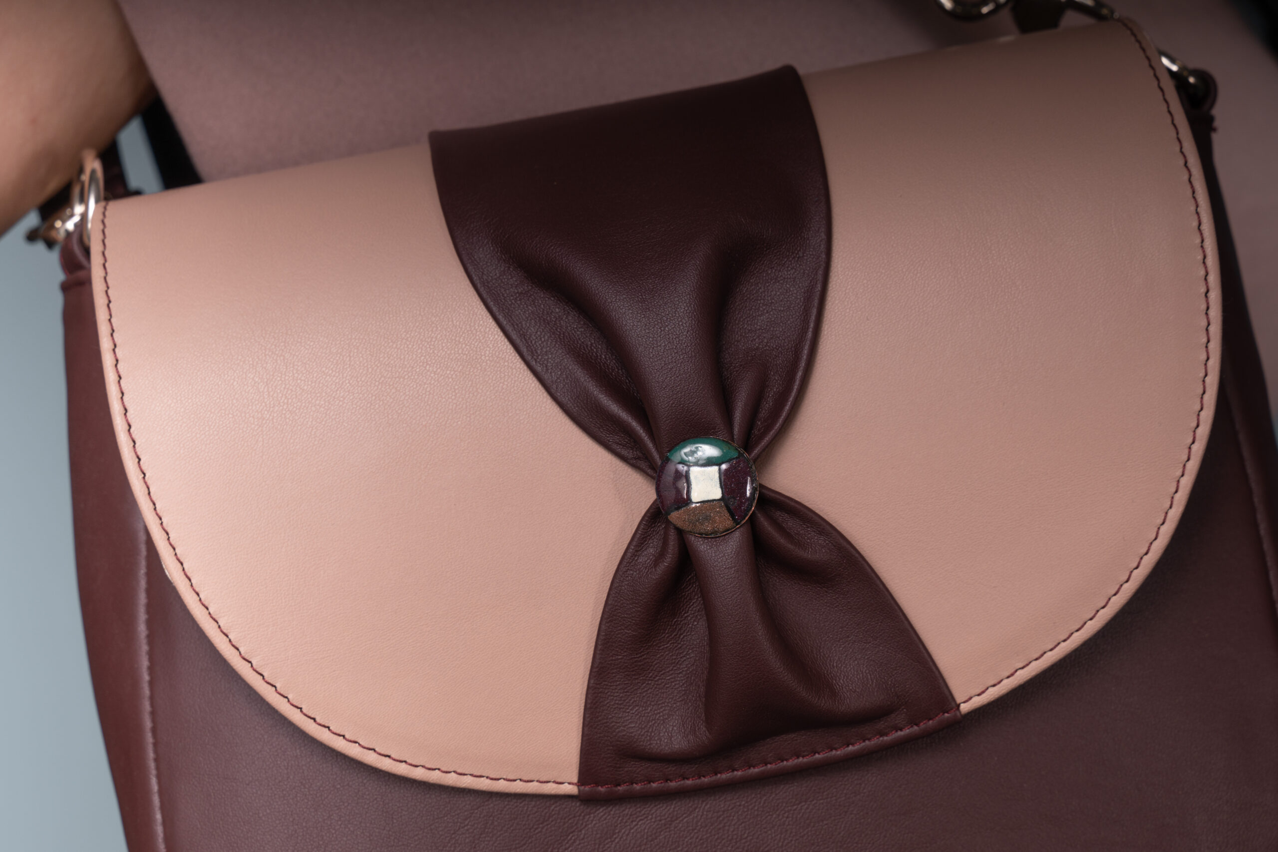 Close-up of the Opacus Leather Bag's sgraffito-enamel button and gathered flap detail.